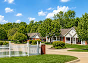 Thumbnail 6 of 19 - A white picket fence surrounds a brick house.