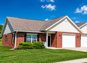 Thumbnail 9 of 19 - A red brick house with a white garage door.