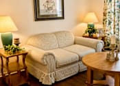 Thumbnail 17 of 19 - A living room with a couch, a table, and a painting on the wall.