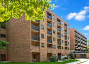 Thumbnail 1 of 3 - A large brick building with balconies and a tree in front.