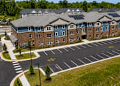 Thumbnail 2 of 7 - A large building with a parking lot in front of it.
