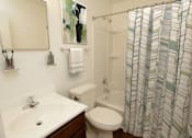 Thumbnail 11 of 25 - A bathroom with a white sink, toilet, and a shower curtain.