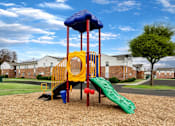 Thumbnail 20 of 25 - A playground with a yellow slide and a blue canopy.