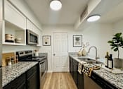 Thumbnail 17 of 40 - A kitchen with black countertops and white cabinets.