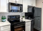 Thumbnail 9 of 38 - a kitchen with black appliances and white cabinets and a black refrigerator