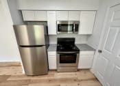 Thumbnail 11 of 14 - a kitchen with a stove a refrigerator and a microwave at Mammoth at the Orchard Apartments, Rogers Arkansas  