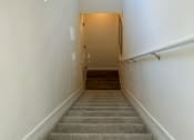 Thumbnail 52 of 65 - a hallway with stairs and white walls and a door to a room with a staircase