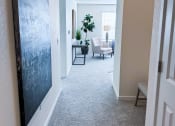 Thumbnail 10 of 65 - a hallway leading to a living room with a blue painting on the wall