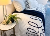 Thumbnail 20 of 65 - a bedroom with a bed with white and black pillows and a nightstand with