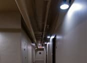 Thumbnail 17 of 17 - A long hallway with wood floors and metal pipes on the ceiling.