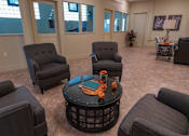 Thumbnail 5 of 17 - A living room with grey chairs and a black coffee table.