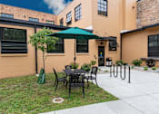 Thumbnail 3 of 17 - A patio with a table and chairs and a green umbrella.