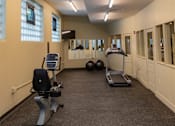 Thumbnail 6 of 17 - A gym with a treadmill, exercise bike, and two exercise balls.
