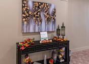 Thumbnail 11 of 17 - A painting of gold leaves hangs on a wall above a black table with a sign that says harvest.