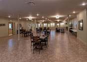 Thumbnail 7 of 17 - A large room with tables and chairs is well lit with natural light.