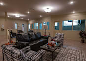 Thumbnail 4 of 17 - A living room with a black couch, a coffee table, and a chair.