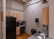Thumbnail 12 of 25 - A kitchen with a black fridge and wooden cabinets.