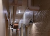 Thumbnail 13 of 25 - A long hallway with a brick wall and wooden floors.