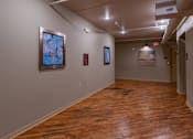 Thumbnail 15 of 25 - A hallway with wood floors and artwork on the walls.