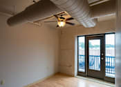 Thumbnail 19 of 25 - A room with a ceiling fan and a door leading outside.