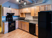 Thumbnail 1 of 25 - A kitchen with wooden cabinets and black appliances.