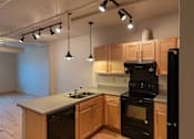 Thumbnail 23 of 25 - A kitchen with wooden cabinets and black appliances.