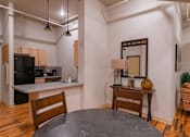 Thumbnail 9 of 25 - A kitchen with a black fridge and a wooden table.