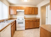 Thumbnail 4 of 7 - A kitchen with a white stove and wooden cabinets.