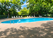 Thumbnail 7 of 7 - A swimming pool surrounded by trees and chairs.