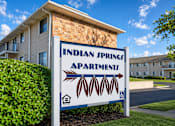 Thumbnail 6 of 7 - A sign for Indian Springs Apartments stands in front of a building.