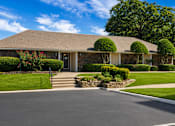 Thumbnail 2 of 7 - A house with a grey roof and a white door is surrounded by greenery.