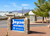 Thumbnail 5 of 8 - A sign for Jaycom Apartments stands in front of a building.