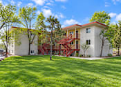 Thumbnail 6 of 10 - A white building with a red staircase in front of it.