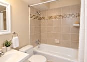 Thumbnail 3 of 10 - A bathroom with a white toilet, sink, and bathtub.