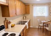 Thumbnail 7 of 10 - A kitchen with wooden cabinets and a white stove top oven.