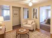 Thumbnail 10 of 10 - A living room with a white chair and a coffee table.