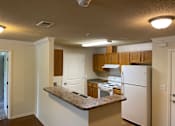 Thumbnail 4 of 15 - A kitchen with white appliances and wooden cabinets.
