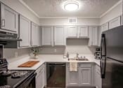 Thumbnail 2 of 18 - A kitchen with black appliances and white cabinets.