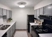 Thumbnail 10 of 18 - A kitchen with a black refrigerator, stove, and cabinets.