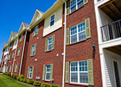 Thumbnail 16 of 20 - A red brick building with green shutters on the windows.