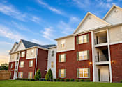 Thumbnail 12 of 20 - A red brick apartment building with a white trim and a balcony on the second floor.