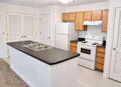 Thumbnail 9 of 20 - A kitchen with white appliances and wooden cabinets.