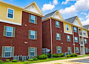 Thumbnail 8 of 20 - A row of red brick apartment buildings with green shutters on the windows.