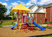 Thumbnail 5 of 20 - A playground with a yellow umbrella and a blue slide.