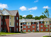 Thumbnail 17 of 20 - Apartment building with a parking lot in front.