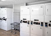 Thumbnail 14 of 18 - A laundry room with a shopping cart and washing machines.