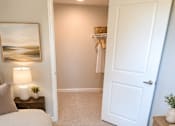 Thumbnail 2 of 12 - A bedroom with a bed, nightstand, and a painting on the wall.