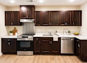 Thumbnail 3 of 12 - A modern kitchen with dark wood cabinets and stainless steel appliances.