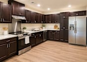 Thumbnail 5 of 12 - A kitchen with dark wood cabinets and stainless steel appliances.