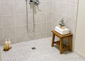 Thumbnail 9 of 12 - A white tiled shower with a wooden stool and candles.